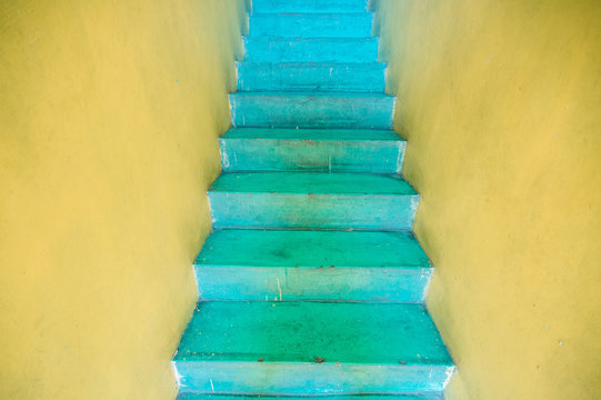 Bright yellow entrance with surreal turquoise colored stairs