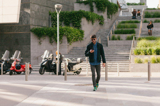 Young man walking and typing at his cellphone