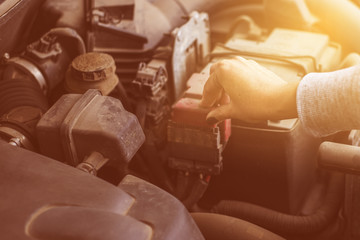 The girl touches the terminals of the car battery