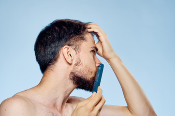 man combing his beard on a light blue background