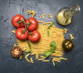 preparation of spaghetti with tomatoes, basil, butter, various seasonings, rich in carbohydrates lunch, on rustic dark blue background, top view