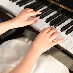 Close-up to the hands of a girl playing the piano keyboard