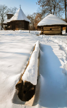 A small traditional wooden church and cottage covered in snow at the Village Museum, Bucharest, Romania