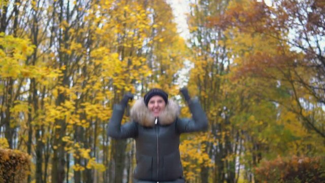 A woman is dancing in an autumn park