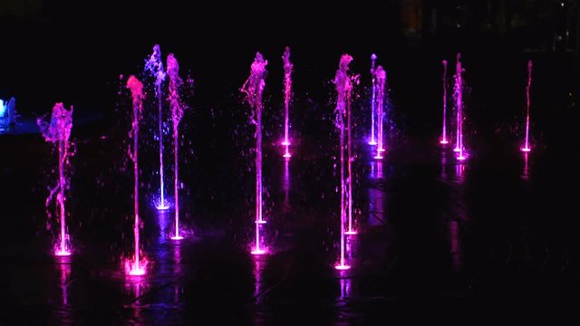 Fountain illuminated at night with purple