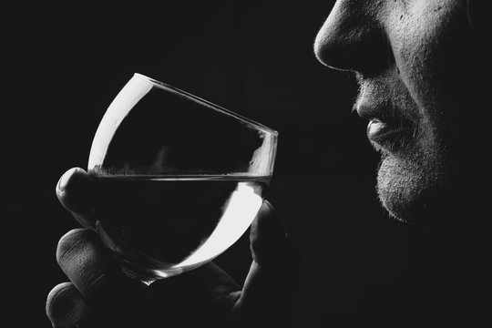 Fototapeta Man tasting or drinking wine or another alcohol from wineglass, black and white photo