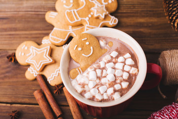 Obraz na płótnie Canvas Gingerbread man bathes in a cup of hot chocolate or cocoa with marshmallow. Gingerbread Man in red cup