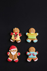 Ginger men with colored  glaze on a black background . Gingerbread. Christmas cookies.
