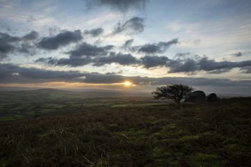 sun peaking over horizon at caradon hill at sunrise with cloudy sky