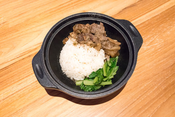 Oriental braised beef with white rice and vegetable in mini iron hot pot isolated