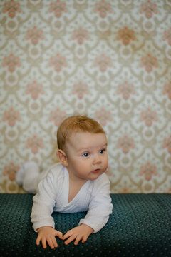 Cute baby girl lying in front of the vintage wallpaper