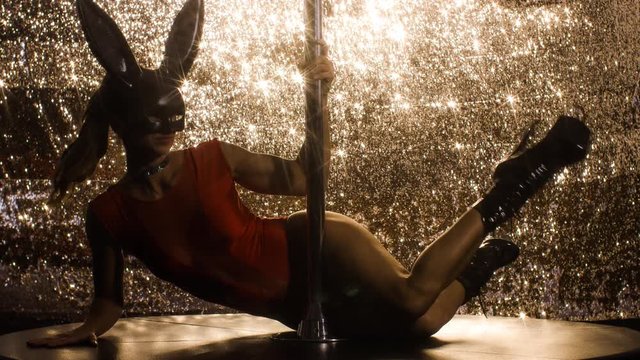 amazing pole dancer with bunny ears showing her skills against sparkling gold background