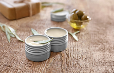 Jars with cream with olive extract on wooden background