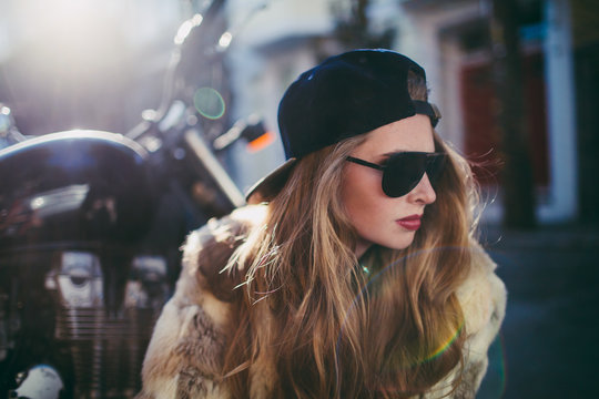 beautiful young stylish girl crouches by motorcycle