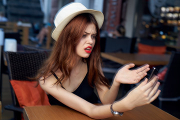 Plakat portrait of a girl in a cafe with a dissatisfied message on the phone