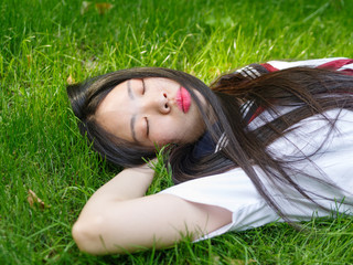 asian girl student in school uniform japanese style lying on meadows.