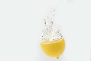 Fototapeta na wymiar lemon falling in water on white background