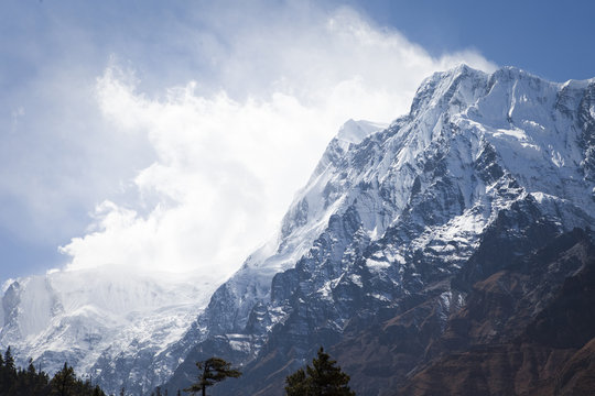 Mountain with strong wind blowing off snow.