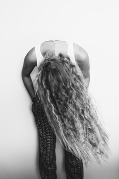 Girl leans forward and swings her long hair in front of her body