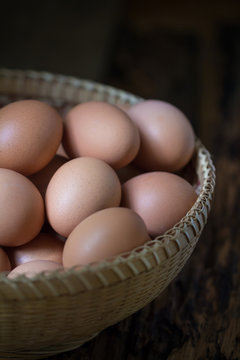 Close up of eggs in a basket on wooden table background