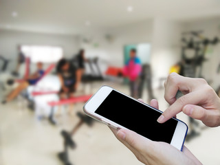 Woman using touch screen mobile phone with blur fitness gymt