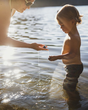 Mother and son collecting stones from lake