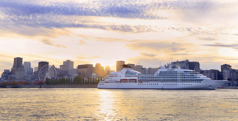 Cruise boat sailing at sunset on St. Lawrence River with skyline of Montreal on the background,...