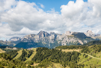 Fototapeta premium panoramic view of mountain ranges in Dolomites with cloudy sky and copy space