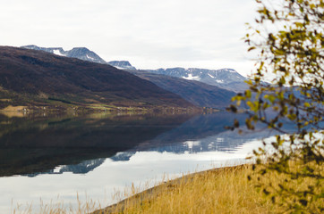 Obraz premium OTEREN, NORWAY: Mountains and reflective lake on a cloudy day
