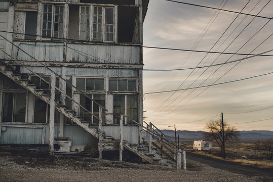 An abandoned building in a dusky desert with distant trailer