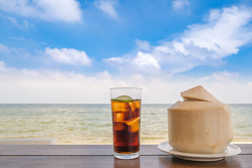 Abstract coconut and soft drink on the table on the sea beach background include copyspace for add text or graphic