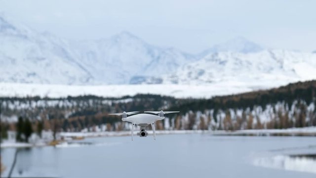 Hovering drone taking pictures of white winter nature.