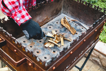 gloved hand kindles fire in grill with long lighter