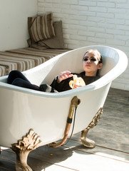 Woman eat banana in white bathtub on wooden floor