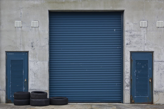 Closed blue gates to a storage area with a pile of old tires in front