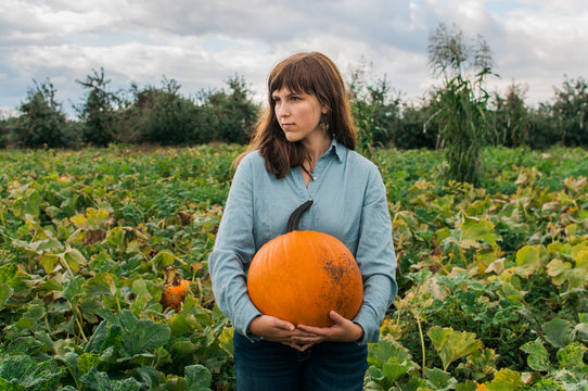 girl holding a pumpkin in a pumpkin patch