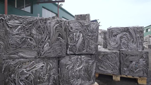 Pressed metal pipes for recycling, sorted garbage is squeezed and stands on a pallet, is on the street in the factory