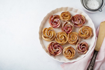 Delicious pies with an apple rose in ceramic form on a light concrete or stone background. Selective focus. Top view.
