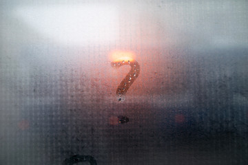 Question inscription on condensed glass with orange light behind