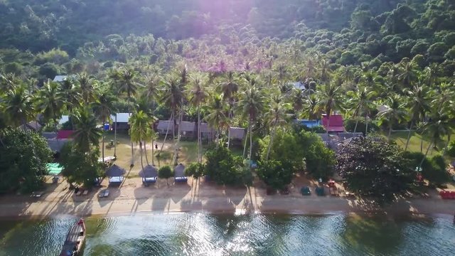 Camera moving from left to right showing a village in paradise with palm trees and backpacker resorts.
