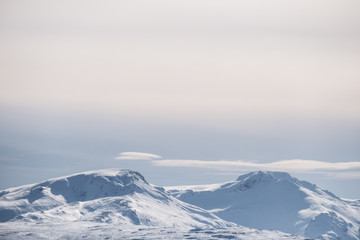 Obraz premium Snow capped mountain peak and blue sky with white clouds in winter, winter landscape in Iceland