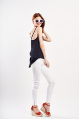 Naklejka premium A cheerful girl in glasses with a dark T-shirt and light pants