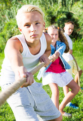 Happy kids tugging war in summer park