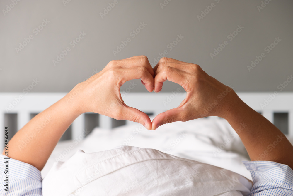 Wall mural Woman is showing a gesture by hand in heart shape