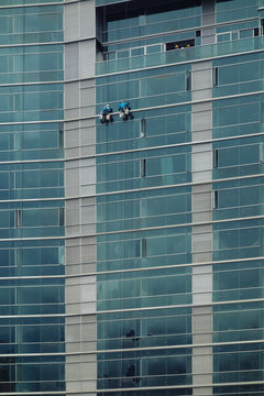 Two workers hanging on outside of a new high rise building