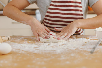 Obraz na płótnie Canvas A young beautiful happy woman sitting at a table with flour, kneading dough and going to prepare a Christmas cakes in the kitchen. Cooking home. Prepare food close up.