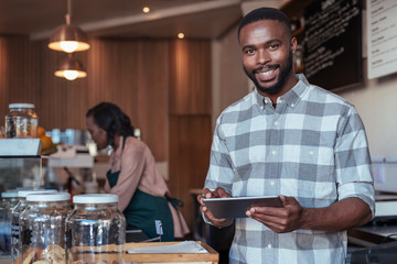 Smiling African entrepreneur working at the counter of his cafe