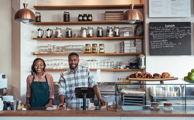 Two smiling African entrepreneurs standing behind their bakery counter