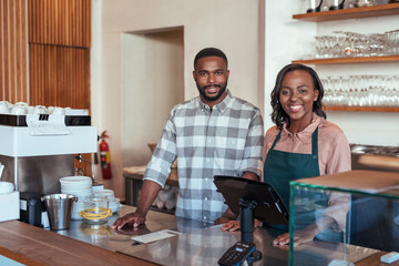 Smiling African entrepreneurs standing at the counter of their bakery