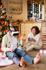 Senior couple in front of Christmas tree with VR goggles.